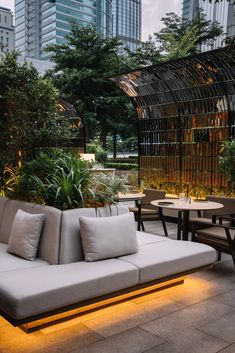 an outdoor seating area with couches and tables in the foreground, surrounded by tall buildings