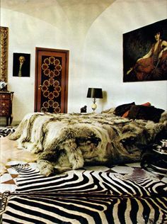 a bedroom with zebra print rugs and pictures on the wall above the bedspread