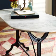 a table with a book on top of it in front of a couch and window