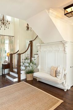 a white couch sitting under a chandelier in a living room next to a stair case