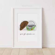 a white frame with a green bowl and brown hat on it next to a wall