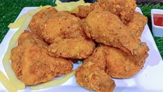 some fried food on a white plate with ketchup and mustard in the background