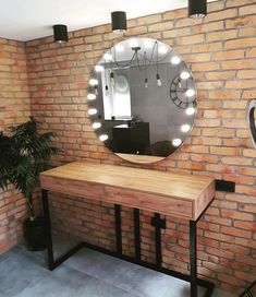 a table with a mirror and lights on it in front of a brick wall