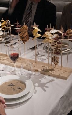 people sitting at a table with food and wine glasses on the table in front of them