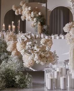 white flowers and candles are arranged in front of a mirror on a table with mirrors behind them