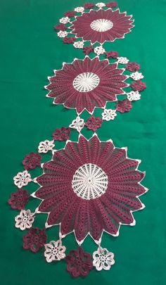 two rows of red doily with white flowers on green fabric, one row is cut in half