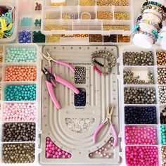 crafting supplies are organized in plastic trays on a white surface with scissors and beads