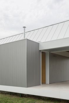 an open garage door on the side of a building with grass in front of it