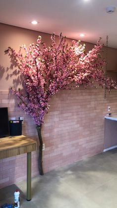 a tree with pink flowers in front of a brick wall