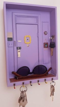 a purple door with some keys hanging from it's sides and two pairs of sunglasses in the middle