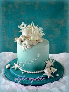 a blue cake with sea shells and pearls on top