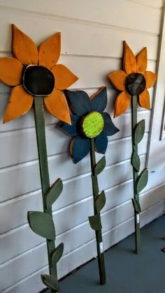 three metal sunflowers are standing next to each other