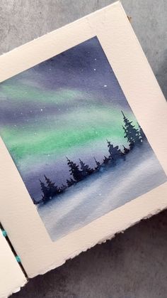 an art project with watercolors on paper depicting the aurora bore and pine trees