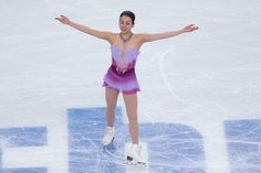 a female figure skating on the ice with her arms out and hands outstretched in front of her