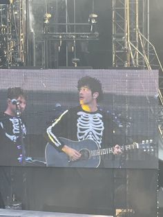 two young men are playing guitars on stage