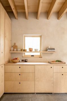 a kitchen with wooden cabinets and shelves on the wall, along with a window above it