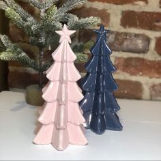 two ceramic christmas trees sitting on top of a table