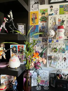 there is a vase with flowers in it on the desk next to pictures and toys