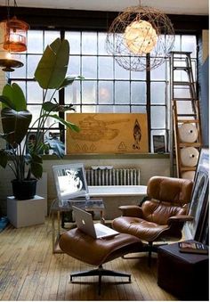 a living room filled with furniture next to a window covered in plants and hanging lights