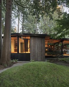 a small house in the middle of a forest with lots of trees and grass around it