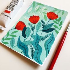 a piece of paper with red flowers on it next to a marker and paintbrush