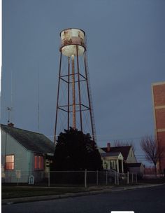 an old water tower sits in the middle of a neighborhood at night with no one around it