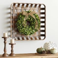 a wreath is hanging on the wall above a table with candles and other decorations around it