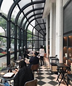 people are sitting at tables in an enclosed area with black and white checkered flooring