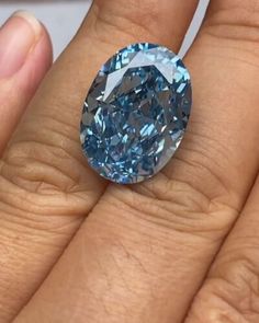 a close up of a person's hand holding a blue diamond