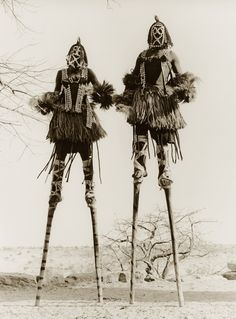 two native american people standing next to each other in front of a tree with no leaves