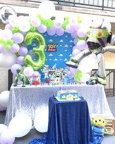 a table topped with balloons and an inflatable toy story 3 sign next to a balloon arch