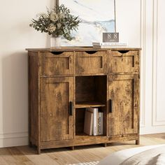 a wooden cabinet with two drawers and a shelf on the top that has books in it