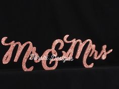 the word mrs spelled in pink glitter on a black background for a wedding cake topper