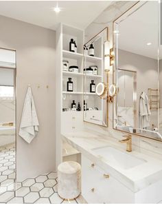 a white bathroom with gold accents and marble counter tops, along with shelves filled with personal care items