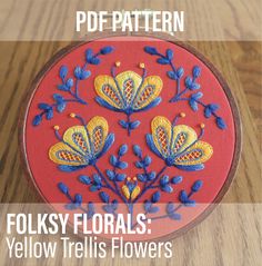 an embroidery project with the text folksy florals yellow iris flowers on red fabric