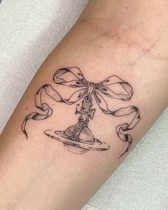 a woman's arm with a tattoo on it that has a hat and ribbon tied around it