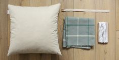 a white pillow sitting on top of a wooden floor next to two pieces of cloth