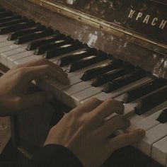 two hands are playing the piano with an old sign behind them that reads kracch