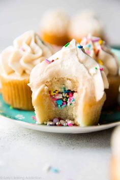 some cupcakes with white frosting and sprinkles on a plate