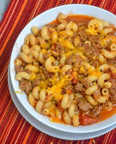 a white bowl filled with pasta and ground beef on top of a colorful place mat