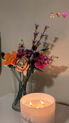 a white candle sitting on top of a table next to a vase filled with flowers