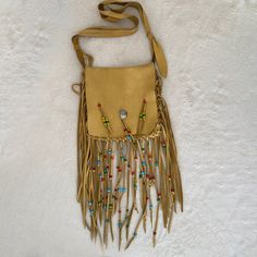 a tan purse with fringes and beads hanging from it's side on a white background