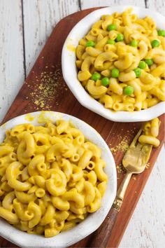 two bowls filled with macaroni and peas on top of a wooden cutting board