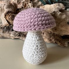 a crocheted mushroom sitting on top of a table next to some driftwood