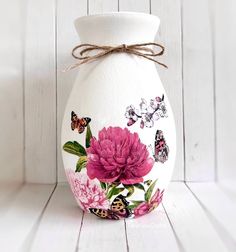 a white vase with pink flowers and butterflies painted on it