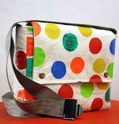 a white purse with multicolored polka dots on it and a black belt around the strap