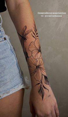 a woman's arm with flowers and leaves tattooed on the side of her arm