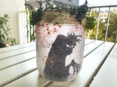 a jar with a shadow of a person on it sitting on a wooden table outside