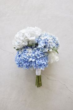 a bouquet of blue and white flowers sitting on top of a marble flooring surface