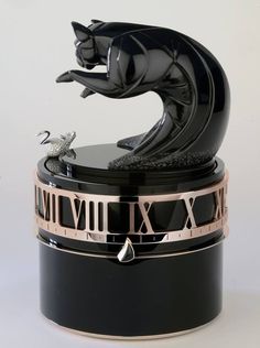 a black cat figurine sitting on top of a clock